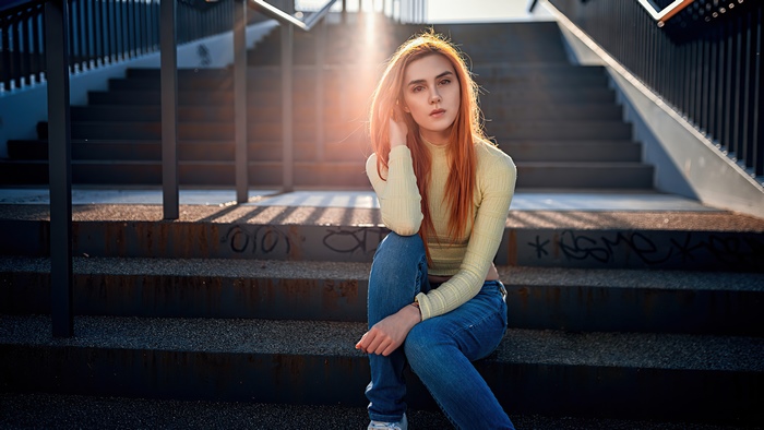 Young woman with red hair sitting on stairs