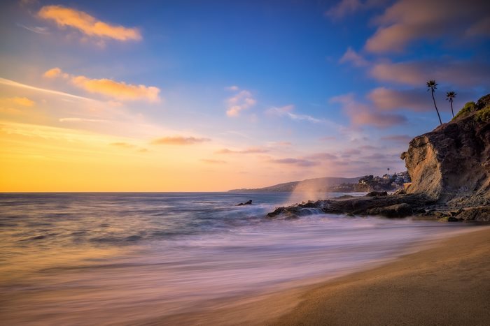 Ocean waves crashing on rocky shore at sunset
