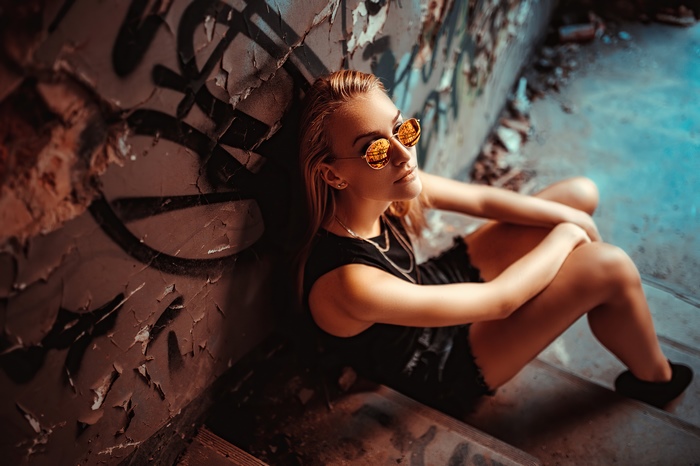 Girl with sunglasses in graffiti-covered urban setting