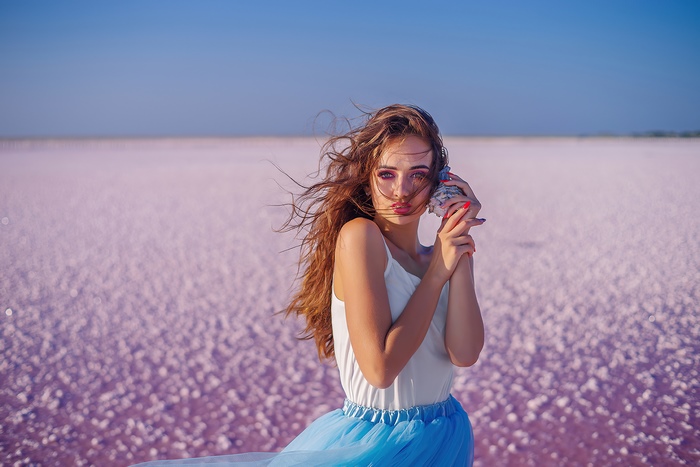 Girl with seashell on pink salt lake