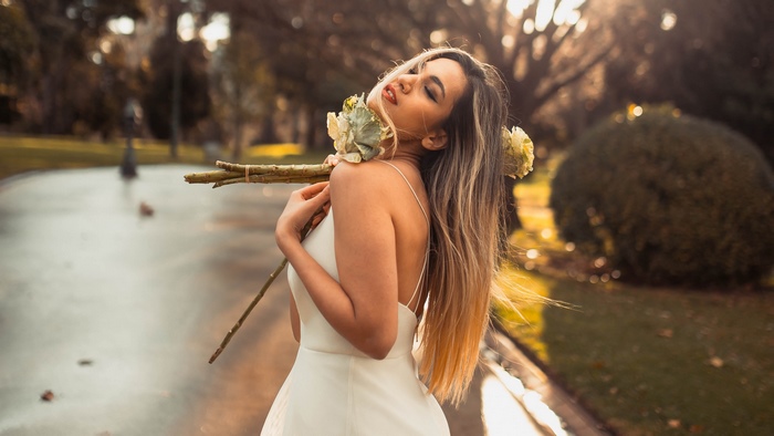 Woman in white dress holding flowers in park