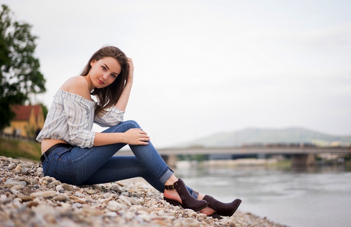 Girl in jeans and off-the-shoulder top by the river
