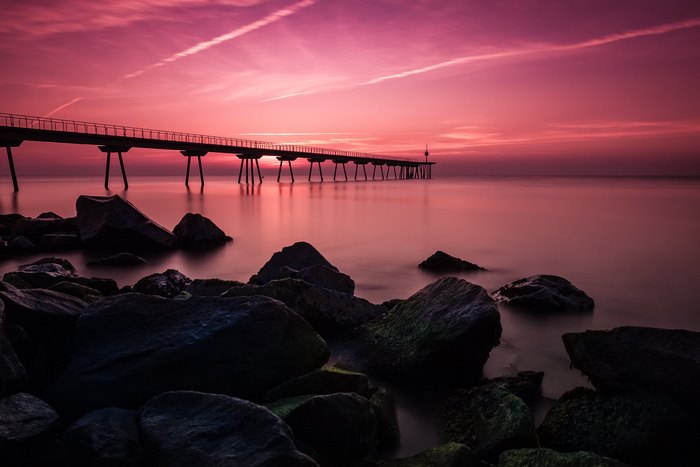 Long exposure of a bridge over water at sunset