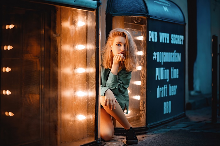 Girl in green shirt near illuminated pub entrance