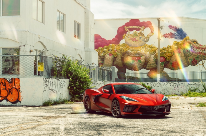 Red Chevrolet Corvette Stingray C8 parked near graffiti and mural