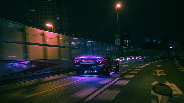 Lamborghini driving on a neon-lit highway at night