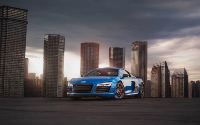 Blue Audi R8 in front of city skyline