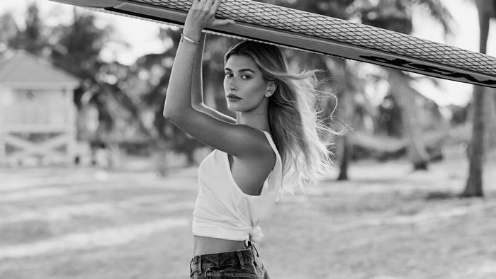 Hailey Bieber holding a surfboard, monochrome