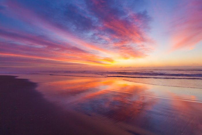 Beach sunrise with colorful clouds and reflections