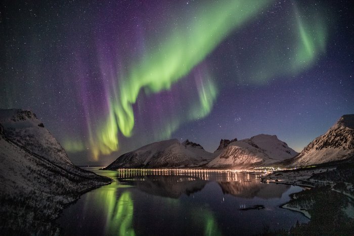 Aurora Borealis over snow-capped mountains and a town