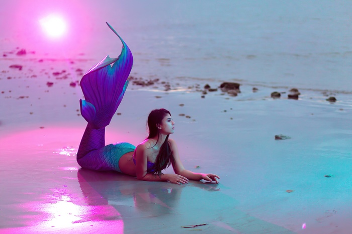 Model in mermaid tail on beach