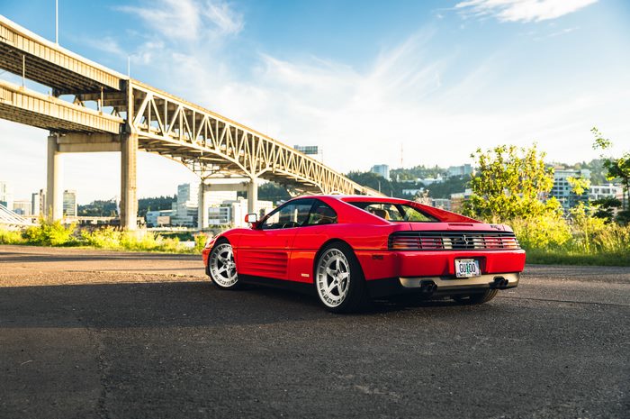 Red Ferrari 348 parked near a bridge