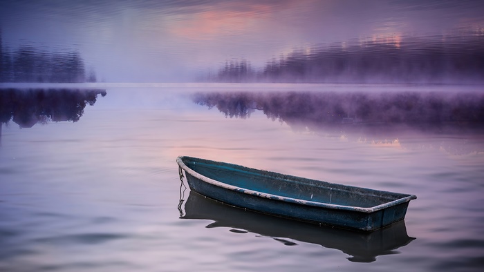 Boat on a misty lake at sunrise