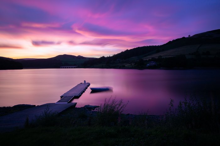 Sunset over a lake with a pier and boat