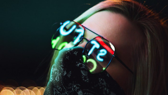 Girl wearing sunglasses reflecting neon lights