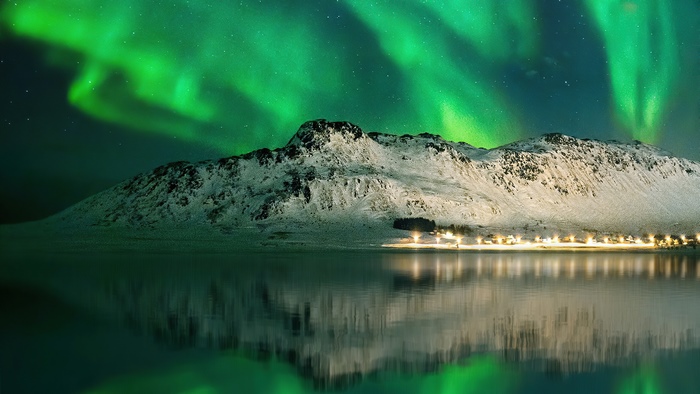 Aurora Borealis over snow-covered mountains and lake