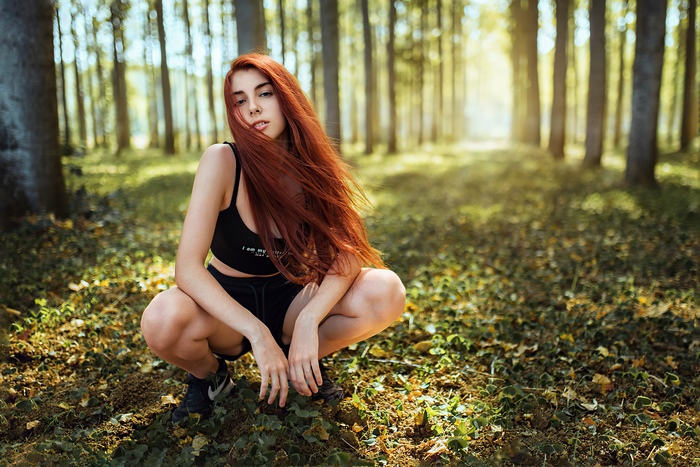 Redhead Model Squatting in Sunlit Forest