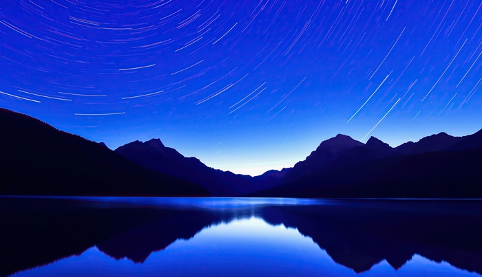 Star trails over a mountain lake at night 4K