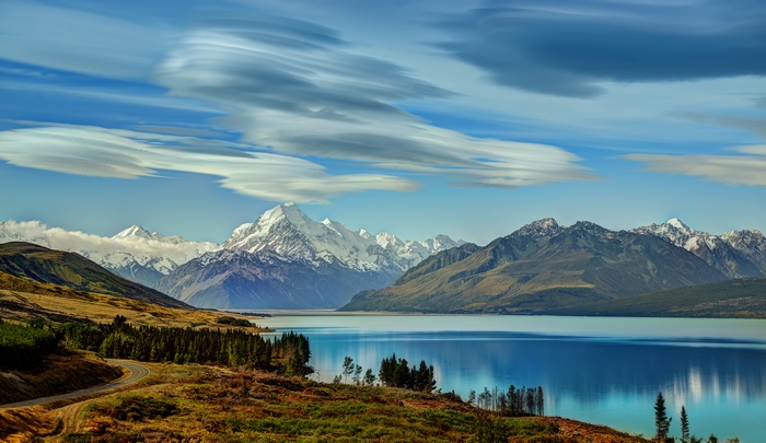 Snow-capped mountains reflected in a lake under a cloudy sky