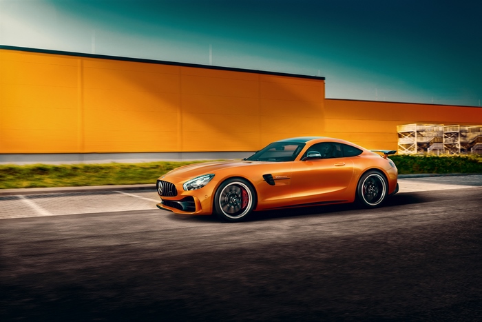 Orange Mercedes-AMG GT parked near a yellow building