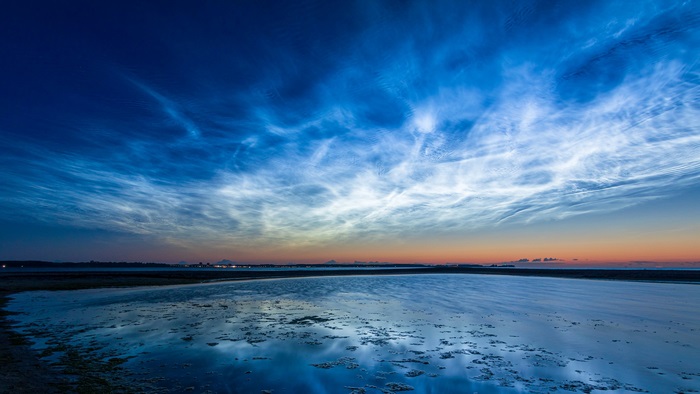 Noctilucent clouds over a body of water at dusk