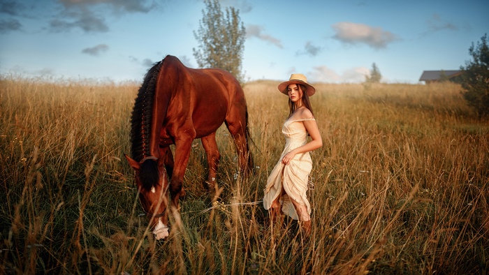 Girl in a hat with a horse in a field