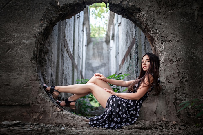 Girl in Black Floral Dress Sitting in Circular Concrete Window