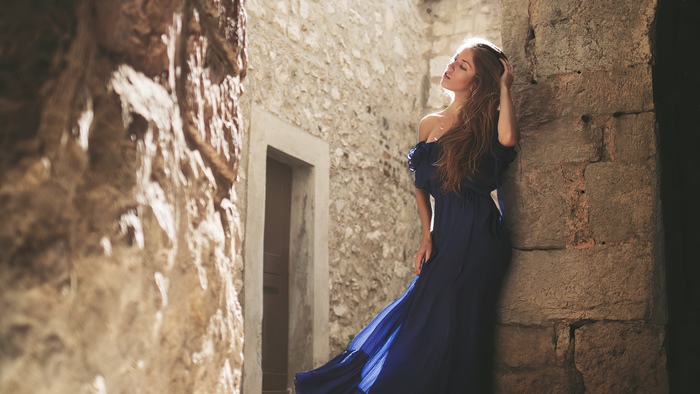 Woman in a blue dress in a stone alley