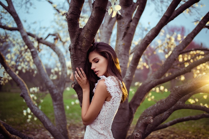 Model in white dress leaning on tree