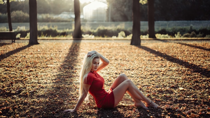 Blonde Model in Red Dress Sitting on Fallen Leaves