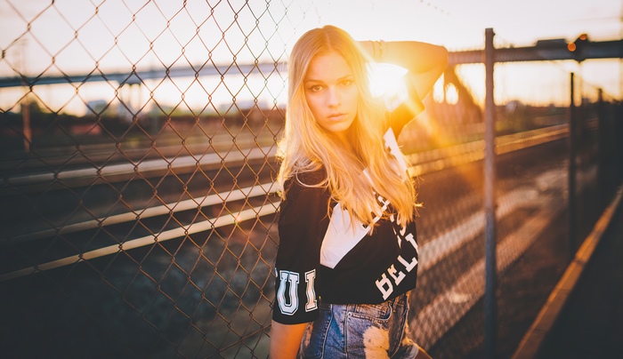 Girl in crop top and denim shorts by fence