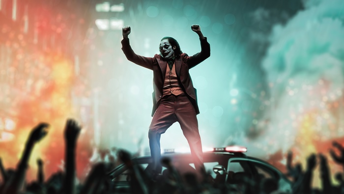 Joker standing on a police car with raised fists
