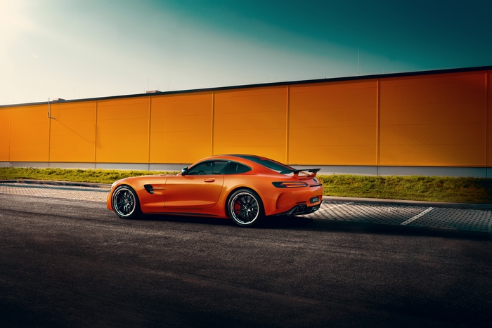Orange Mercedes-AMG GT parked near a yellow building