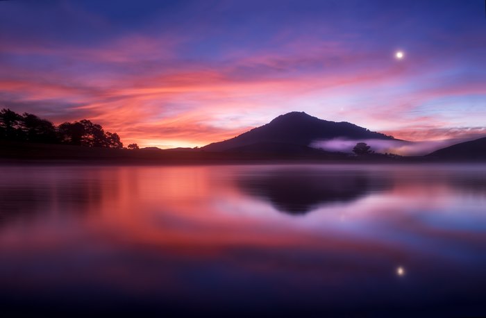Sunset over a misty lake with mountains