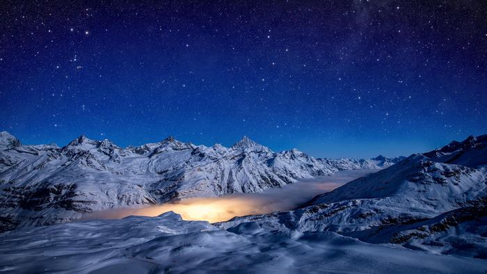 Snowy mountains under a starry night sky 4K