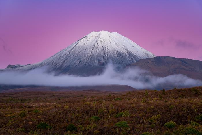 Snow-capped mountain with purple sky and fog
