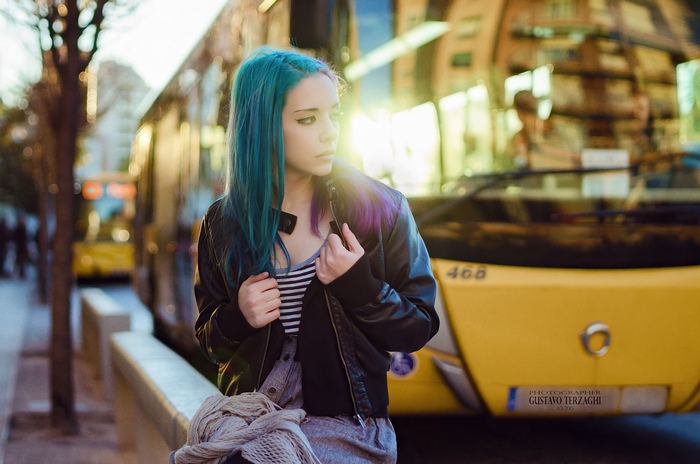 Girl with blue hair by a yellow bus