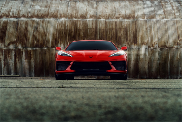 Red Chevrolet Corvette C8 in front of corrugated metal wall