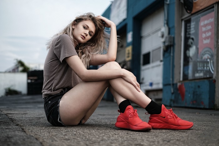 Model in denim shorts and red sneakers