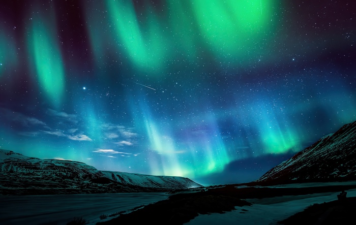 Aurora Borealis over snowy mountains and lake
