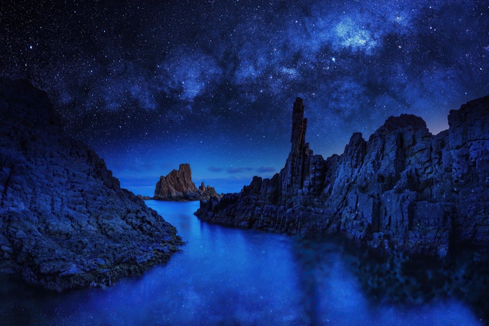 Starry Night Sky Over Rocky Blue Sea