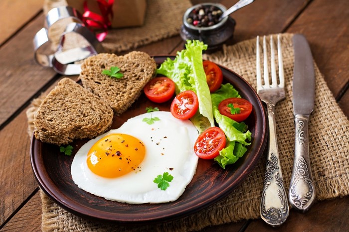 Heart-shaped fried egg with toast and salad
