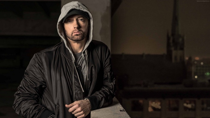Eminem wearing a hoodie and bomber jacket