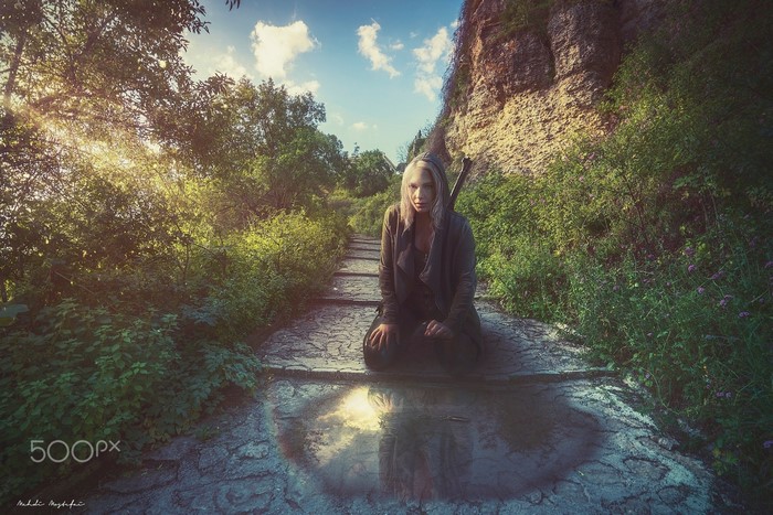Woman kneeling on stone steps in a forest with sunlight