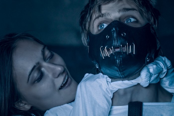 Woman strangling man wearing Hannibal Lecter mask