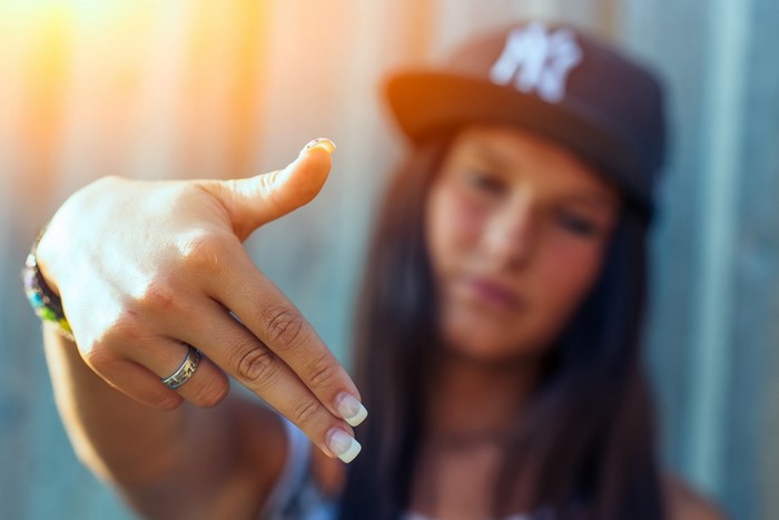 Girl in a baseball cap making a hand gesture
