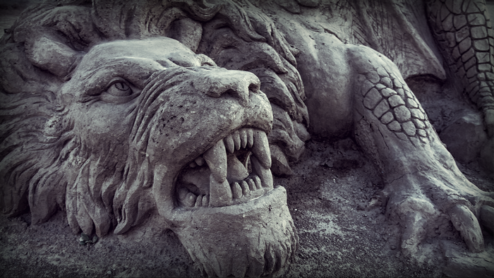 Stone sculpture of a lion with open mouth and scales
