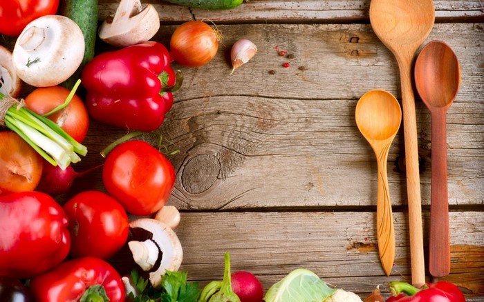 Fresh vegetables and wooden spoons on a rustic surface