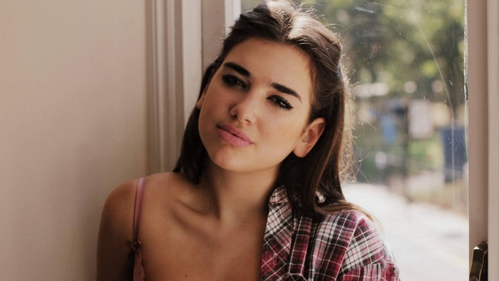 Dua Lipa posing by a window