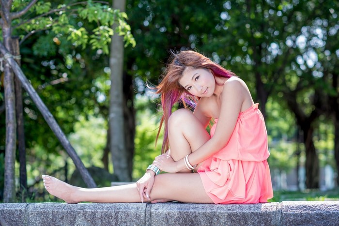 Woman in Pink Strapless Dress Sitting Outdoors